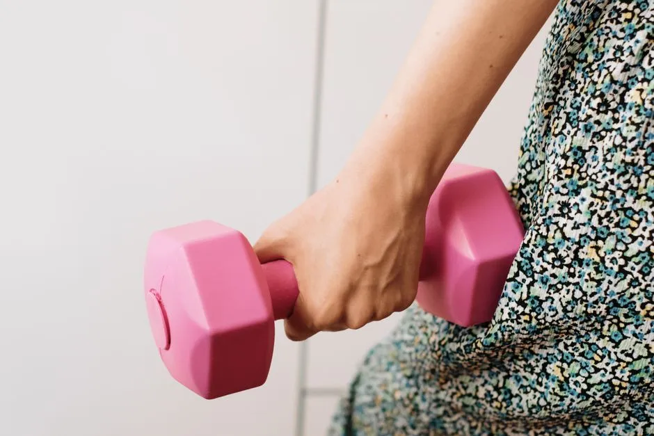 Hånd griper en rosa manual under styrketrening med løsnegler