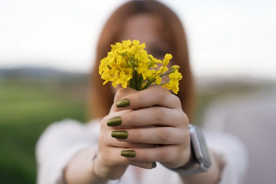 Kvinne holder blomster med lange velholdte naturlige negler