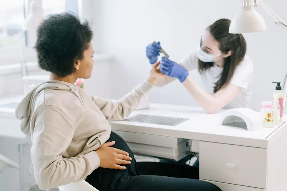 Nærbilde av gravid kvinnes hender under en skånsom manikyr med press-on negler gravid
